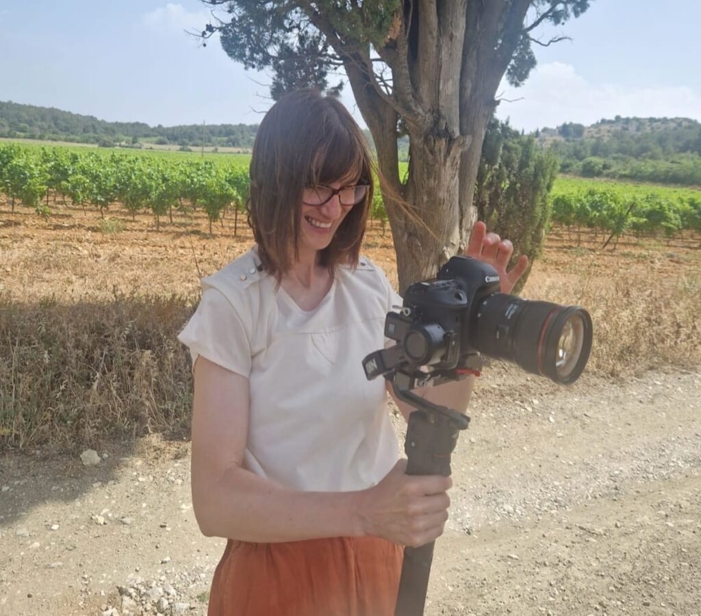 Une vidéaste tient sa caméra entre ses mains pour filmer un mariage.